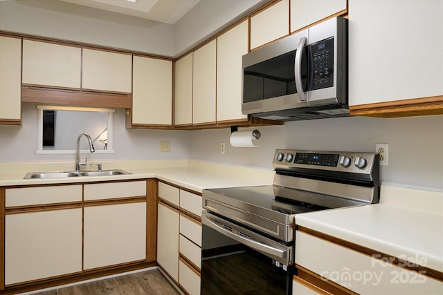 kitchen featuring wood finished floors, stainless steel appliances, a sink, and light countertops