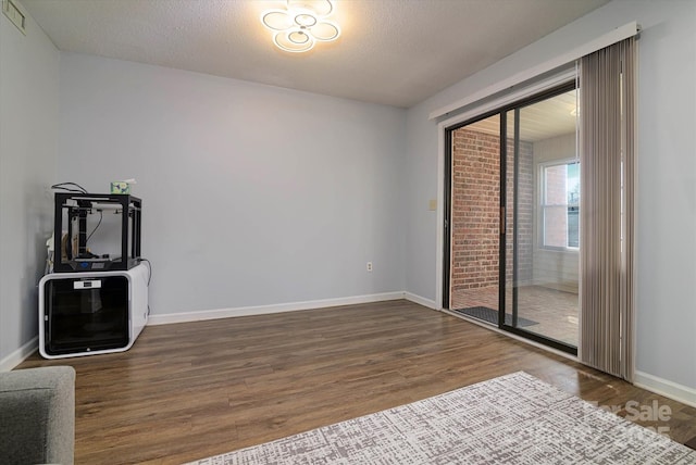 unfurnished room featuring wood finished floors, visible vents, and baseboards