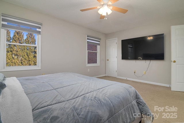 carpeted bedroom with ceiling fan, multiple windows, and baseboards