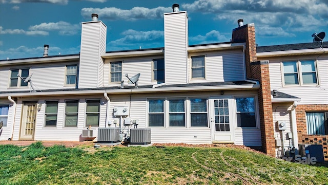 rear view of house featuring a lawn and central AC