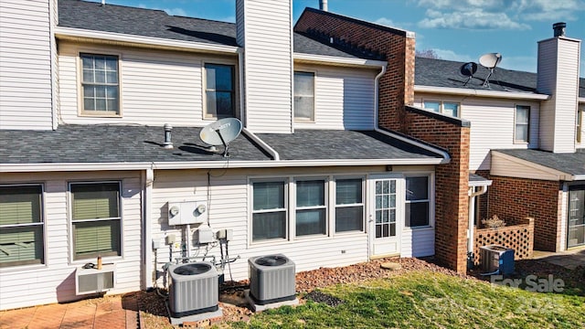 back of house with a shingled roof, a chimney, and central air condition unit