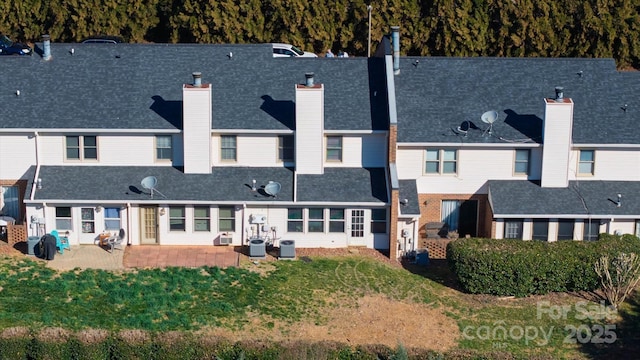 rear view of house with a patio, a chimney, a residential view, and a lawn