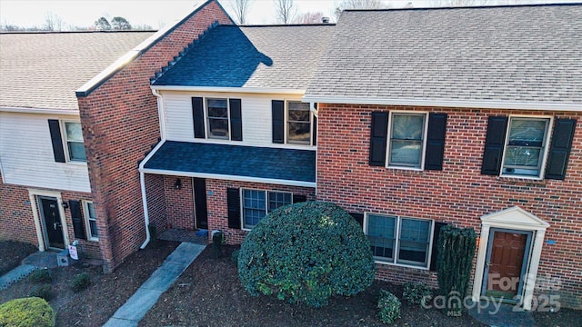 view of front of property featuring a shingled roof and brick siding