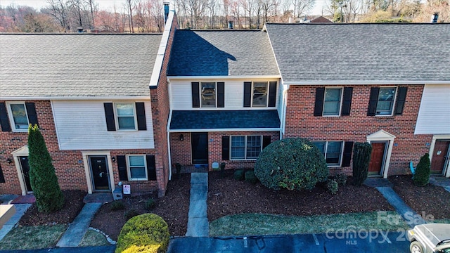 townhome / multi-family property featuring a shingled roof and brick siding