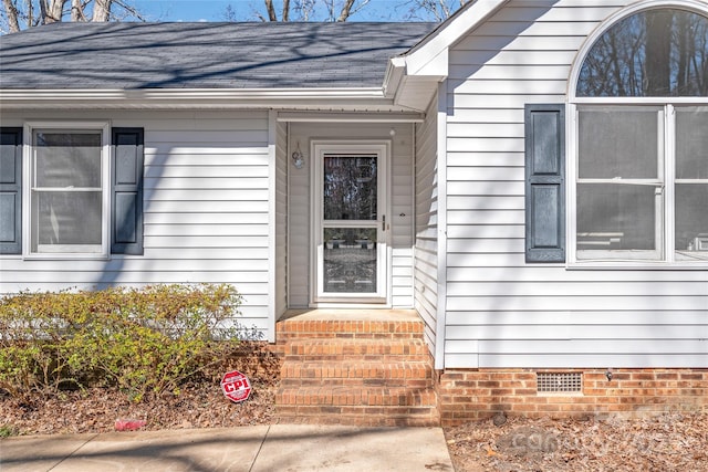 view of exterior entry featuring crawl space and roof with shingles