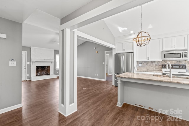 kitchen with light stone counters, stainless steel appliances, decorative backsplash, dark wood-type flooring, and white cabinets