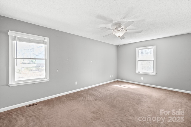 carpeted spare room with baseboards, visible vents, ceiling fan, and a textured ceiling