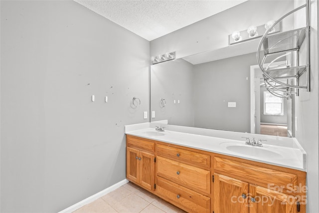 bathroom with a textured ceiling, double vanity, tile patterned flooring, and a sink