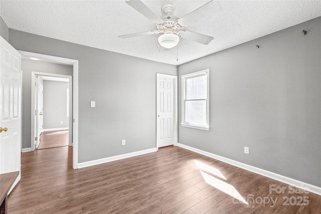 unfurnished bedroom with a textured ceiling, ceiling fan, wood finished floors, baseboards, and a closet