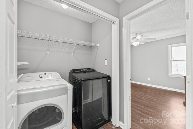 laundry area featuring laundry area, baseboards, wood finished floors, a textured ceiling, and washing machine and dryer