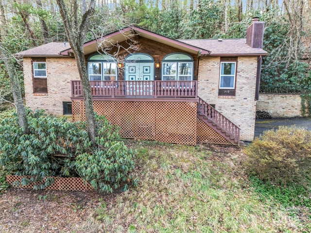 view of front of home with stairs, a porch, brick siding, and a chimney