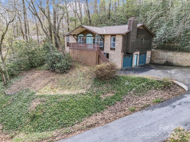 view of front of property featuring aphalt driveway, stairway, an attached garage, brick siding, and a chimney