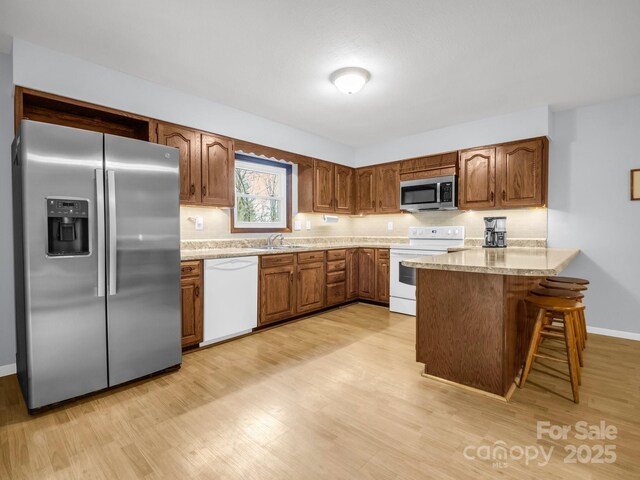 232 Stonebrook Dr, Hendersonville, NC 28791 - kitchen with stainless steel appliances, a peninsula, light wood-style flooring, brown cabinets, and a sink