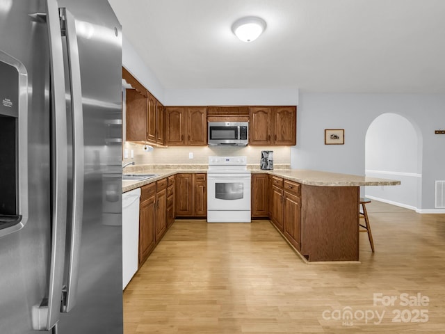 232 Stonebrook Dr, Hendersonville, NC 28791 - kitchen with stainless steel appliances, a peninsula, brown cabinetry, and light wood-type flooring