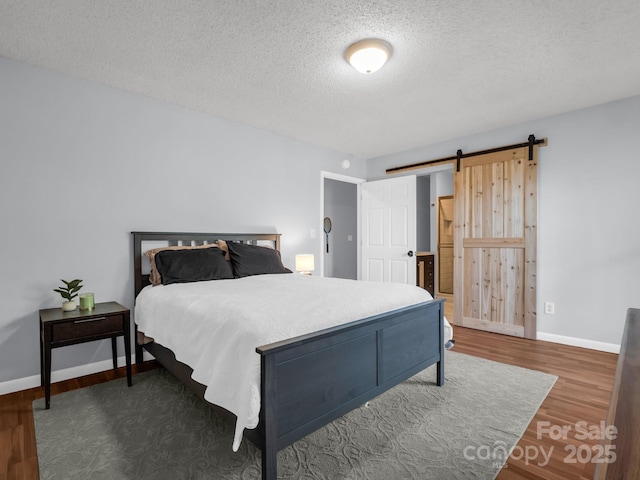 232 Stonebrook Dr, Hendersonville, NC 28791 - bedroom featuring wood finished floors, a barn door, baseboards, and a textured ceiling