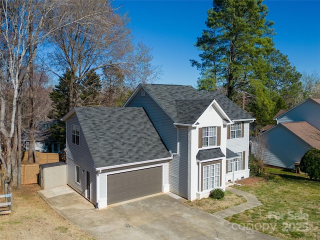 view of front of property with a garage, driveway, roof with shingles, fence, and a front yard