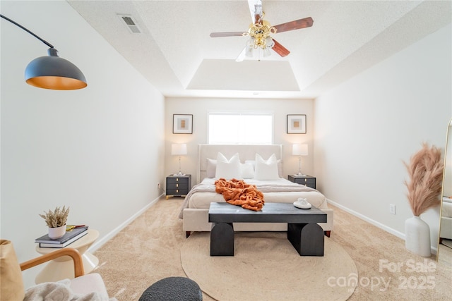 bedroom with a ceiling fan, a tray ceiling, light carpet, and baseboards