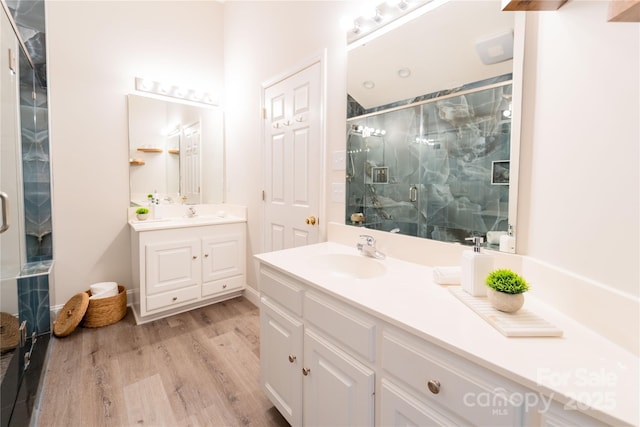 full bath with wood finished floors, two vanities, a sink, and a shower stall