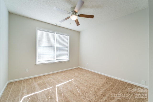 carpeted spare room featuring a ceiling fan, visible vents, a textured ceiling, and baseboards