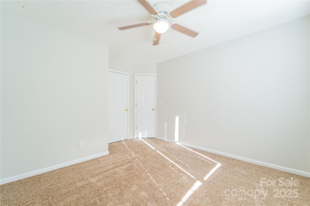 carpeted spare room featuring ceiling fan and baseboards