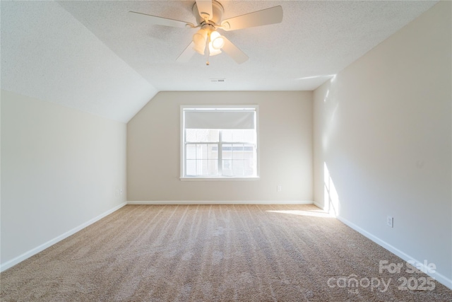 additional living space featuring carpet, vaulted ceiling, a textured ceiling, ceiling fan, and baseboards