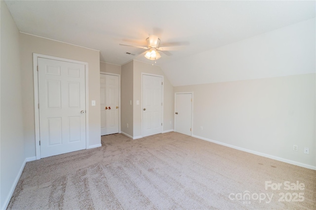 interior space with lofted ceiling, carpet floors, a ceiling fan, visible vents, and baseboards