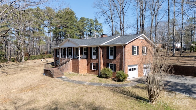 view of front facade with an attached garage, brick siding, stairs, driveway, and a chimney