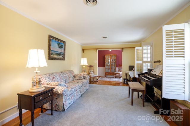 living area featuring ornamental molding, visible vents, baseboards, and wood finished floors