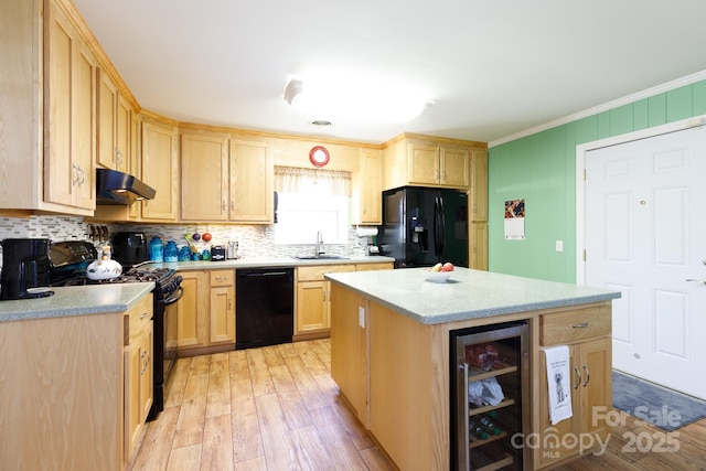 kitchen featuring wine cooler, under cabinet range hood, light brown cabinetry, black appliances, and a sink