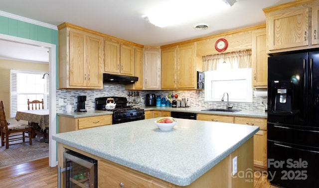 kitchen featuring wine cooler, light brown cabinetry, a sink, under cabinet range hood, and black appliances