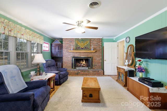 living room with a ceiling fan, a brick fireplace, visible vents, and crown molding