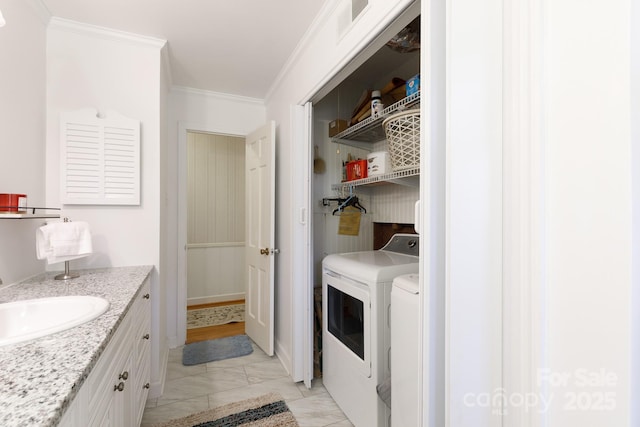 laundry area with laundry area, a sink, marble finish floor, washing machine and clothes dryer, and crown molding