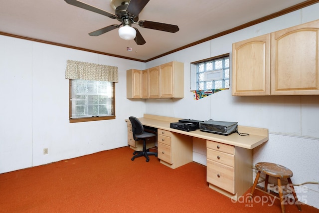 carpeted office featuring ceiling fan, ornamental molding, and built in desk