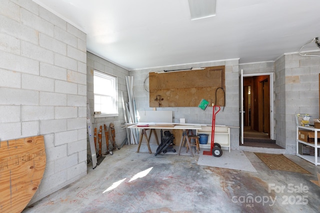 misc room featuring concrete block wall, concrete flooring, and a workshop area