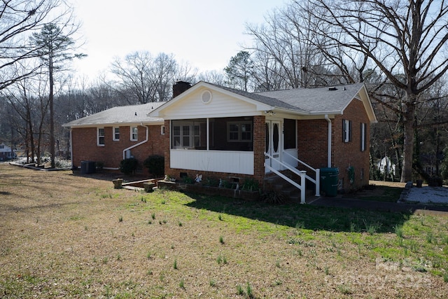 single story home featuring brick siding, a chimney, and a front yard