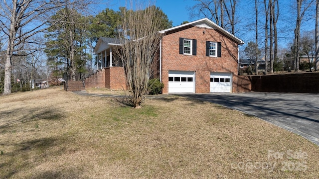 view of side of home with driveway, stairway, an attached garage, a yard, and brick siding