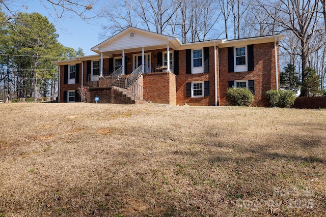 view of front of property featuring covered porch, a front lawn, and brick siding