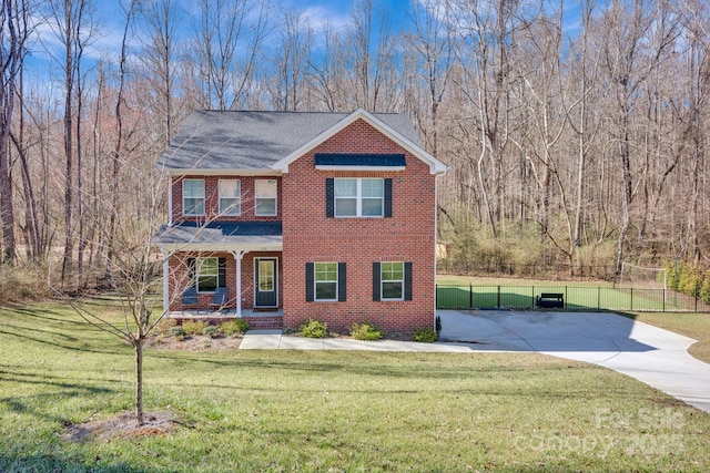 view of front of home with covered porch, brick siding, a front yard, and fence