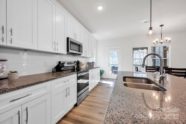 kitchen featuring decorative backsplash, light wood-style flooring, stainless steel appliances, white cabinetry, and a sink