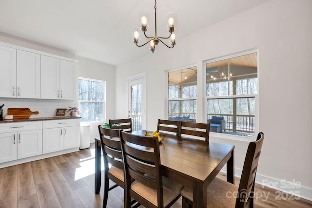 dining area with light wood-type flooring and an inviting chandelier