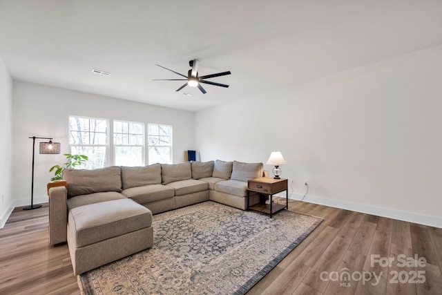 living area with a ceiling fan, visible vents, baseboards, and wood finished floors