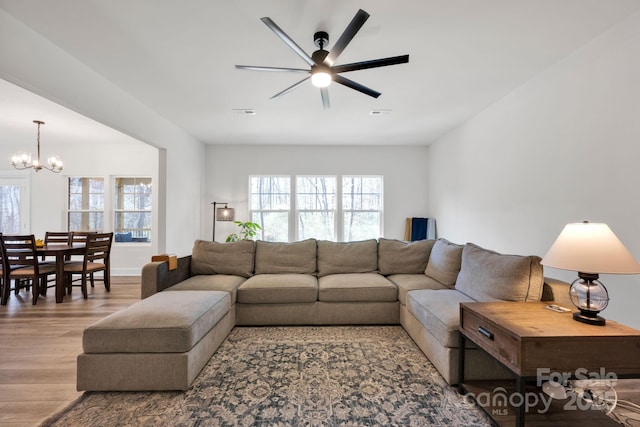 living room with ceiling fan with notable chandelier, wood finished floors, and visible vents