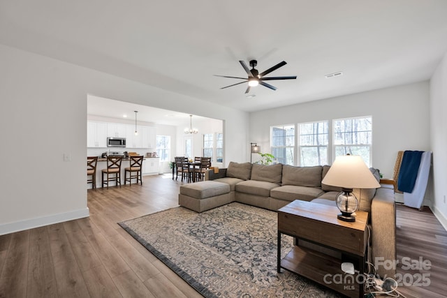 living area with wood finished floors, visible vents, and baseboards