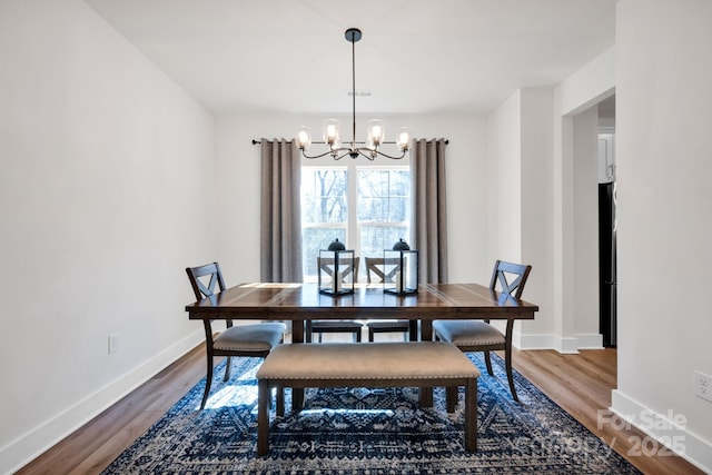 dining room with baseboards, visible vents, a chandelier, and wood finished floors