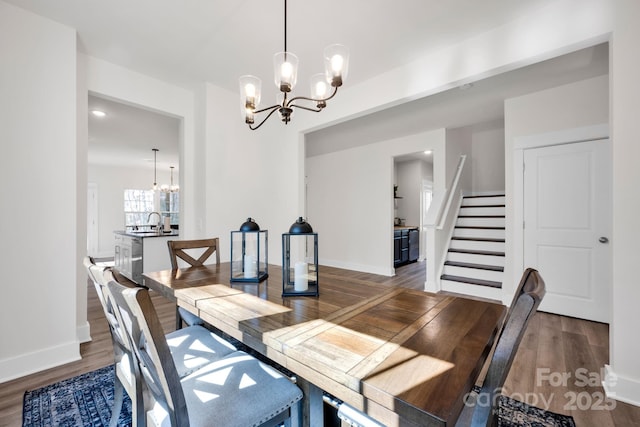 dining room featuring a chandelier, wood finished floors, stairs, and baseboards