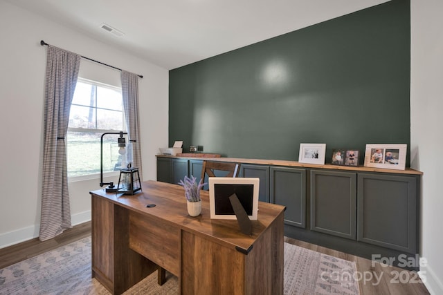 office area with light wood-style flooring, visible vents, and baseboards