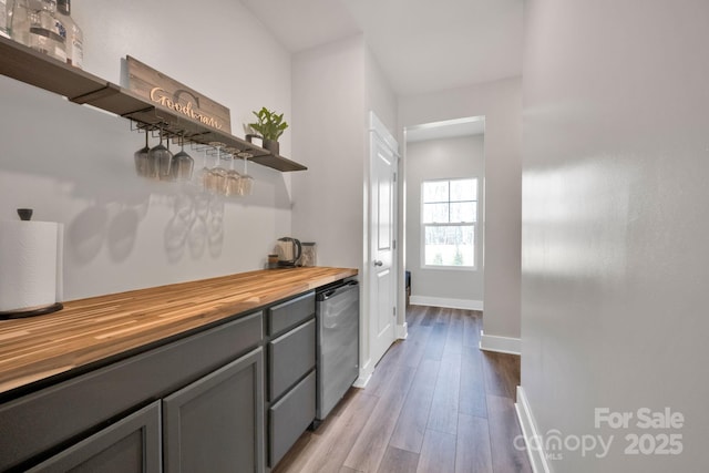 bar with baseboards, a dry bar, and light wood finished floors