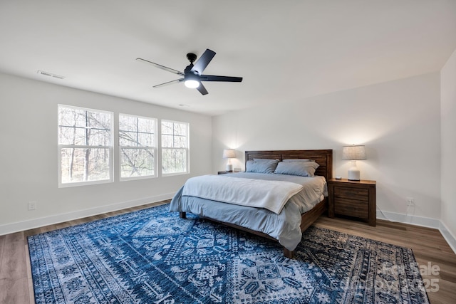 bedroom featuring baseboards, visible vents, ceiling fan, and wood finished floors