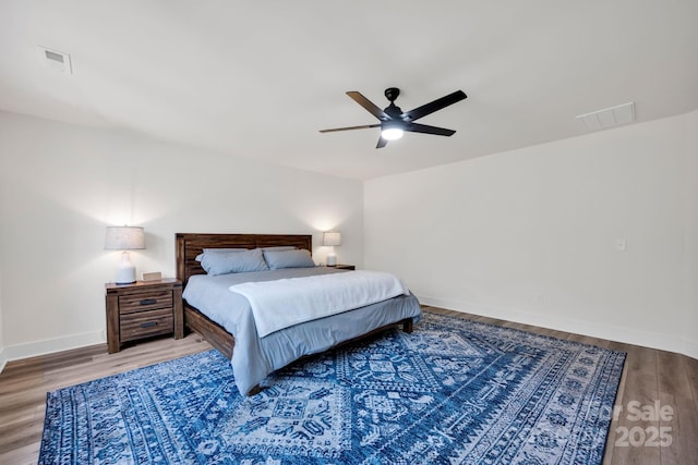 bedroom with baseboards, visible vents, ceiling fan, and wood finished floors