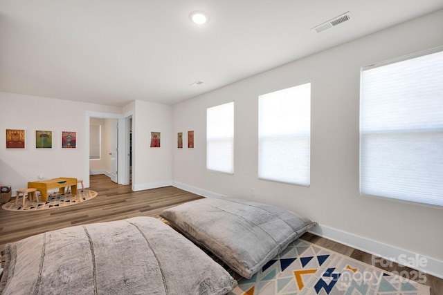 bedroom with baseboards, visible vents, and wood finished floors